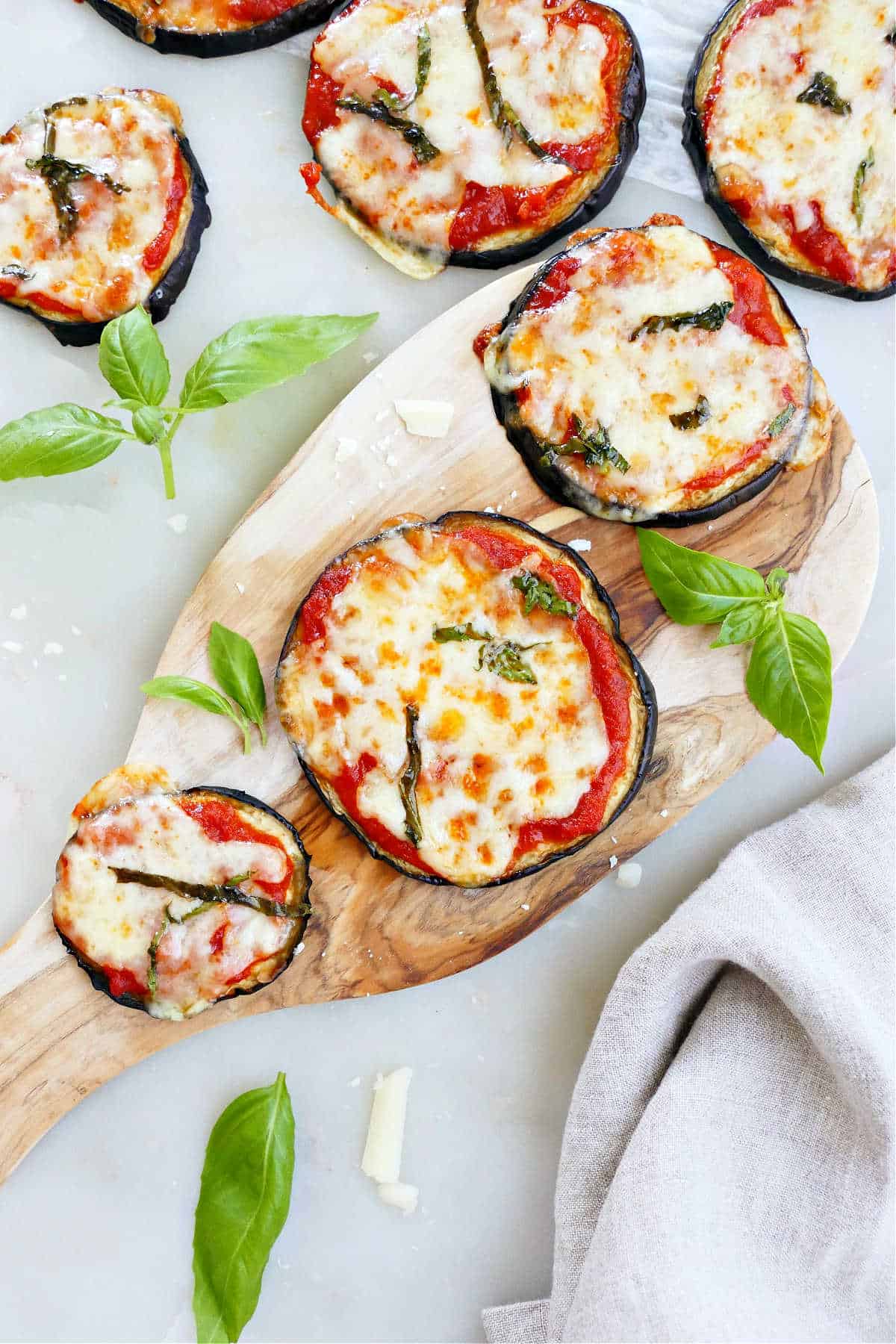 eggplant pizza bites on a wooden slab and counter next to each other