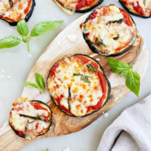 eggplant pizza bites on a wooden slab and counter next to each other