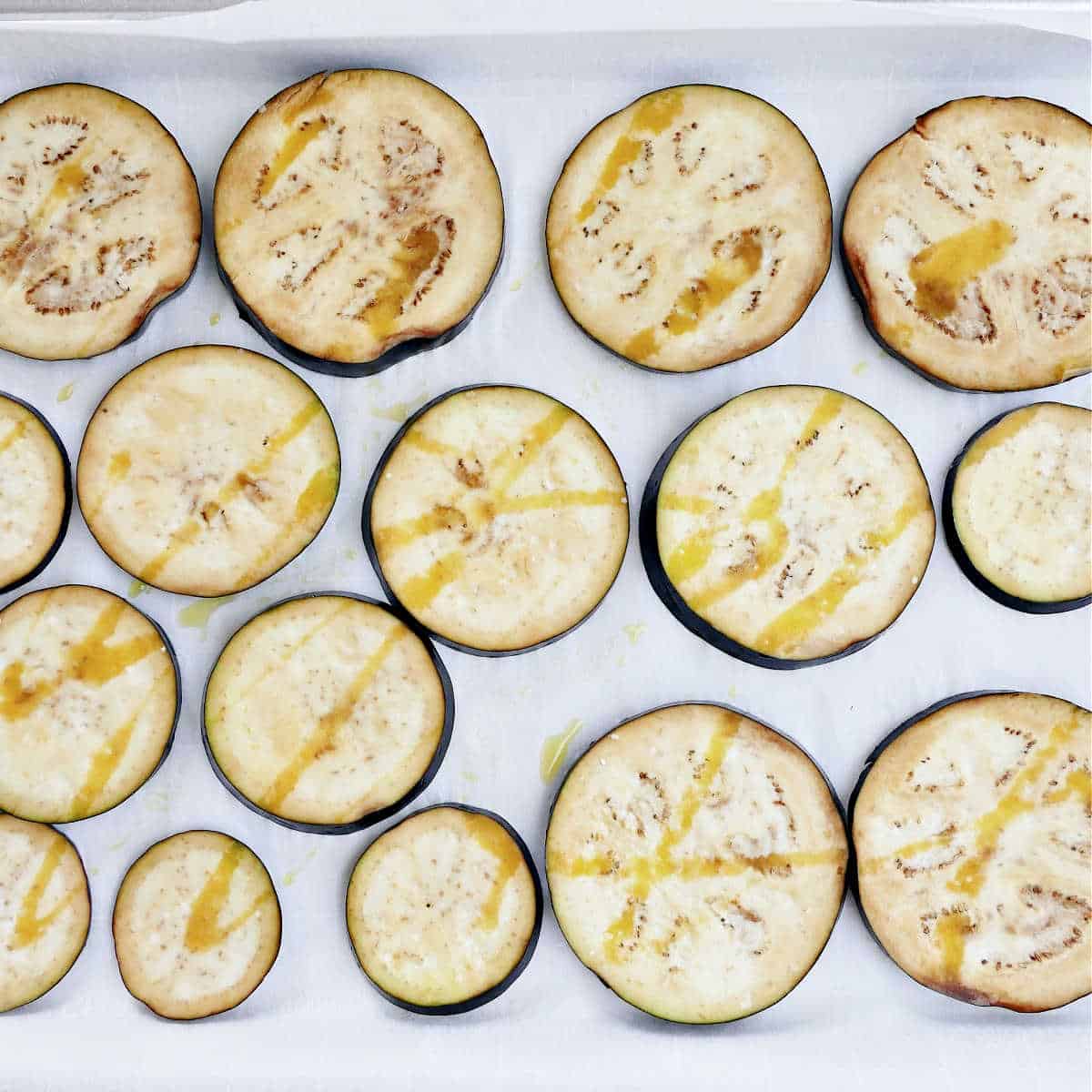 eggplant rounds drizzled with olive oil on a lined baking sheet