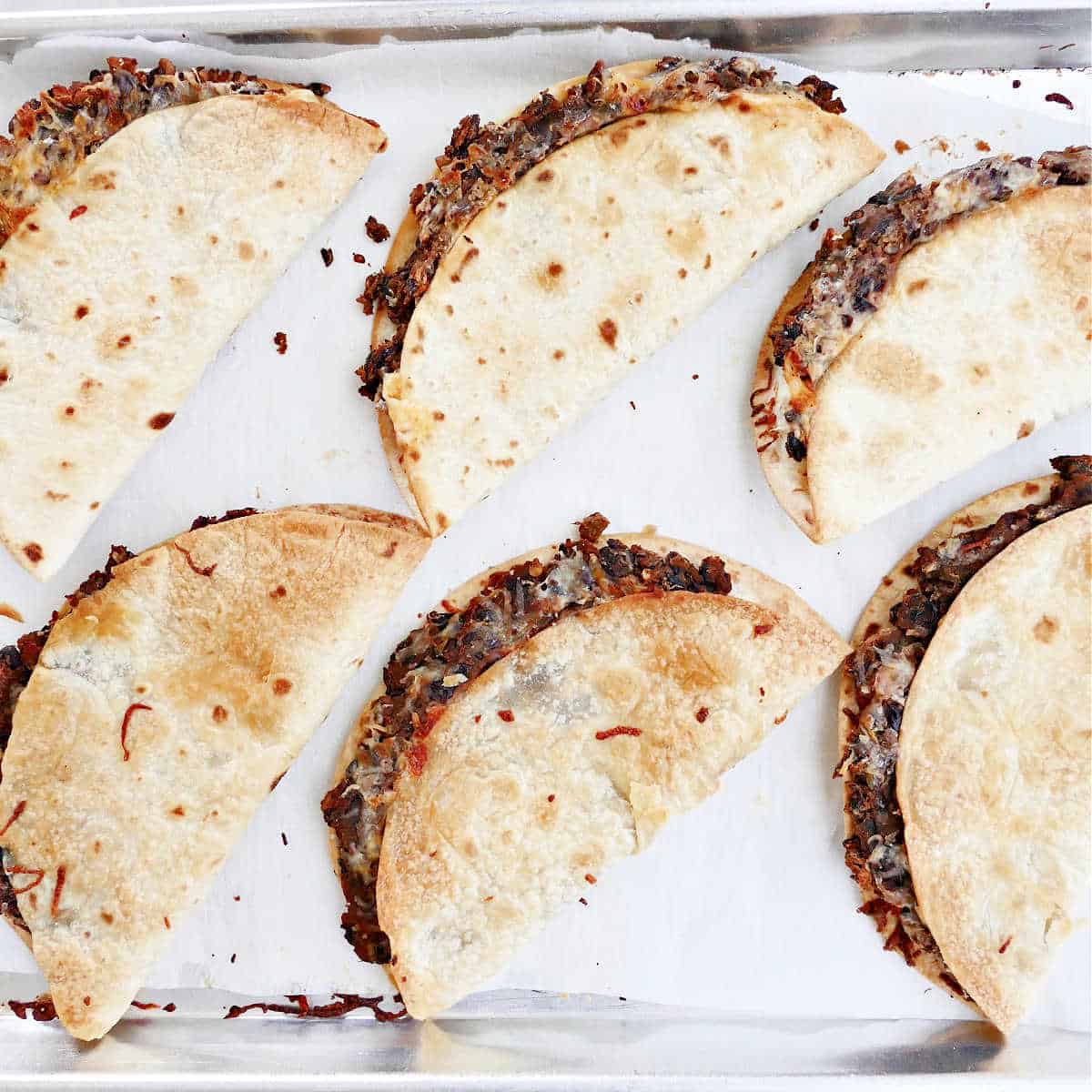 crispy black bean tacos on a lined baking sheet after cooking