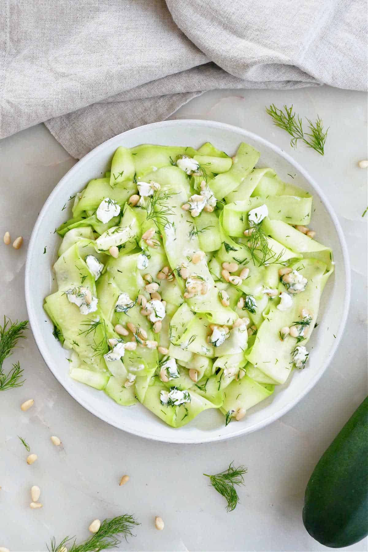 zucchini ribbons with nuts, cheese, herbs, and dressing on a plate