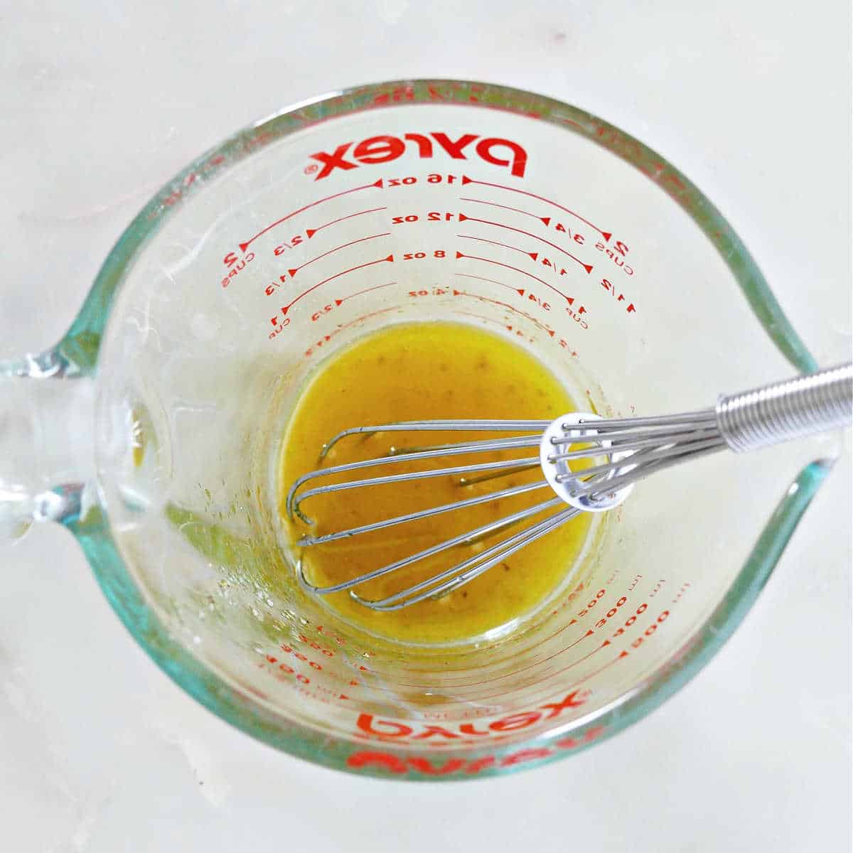 lemon dressing being whisked in a glass measuring cup