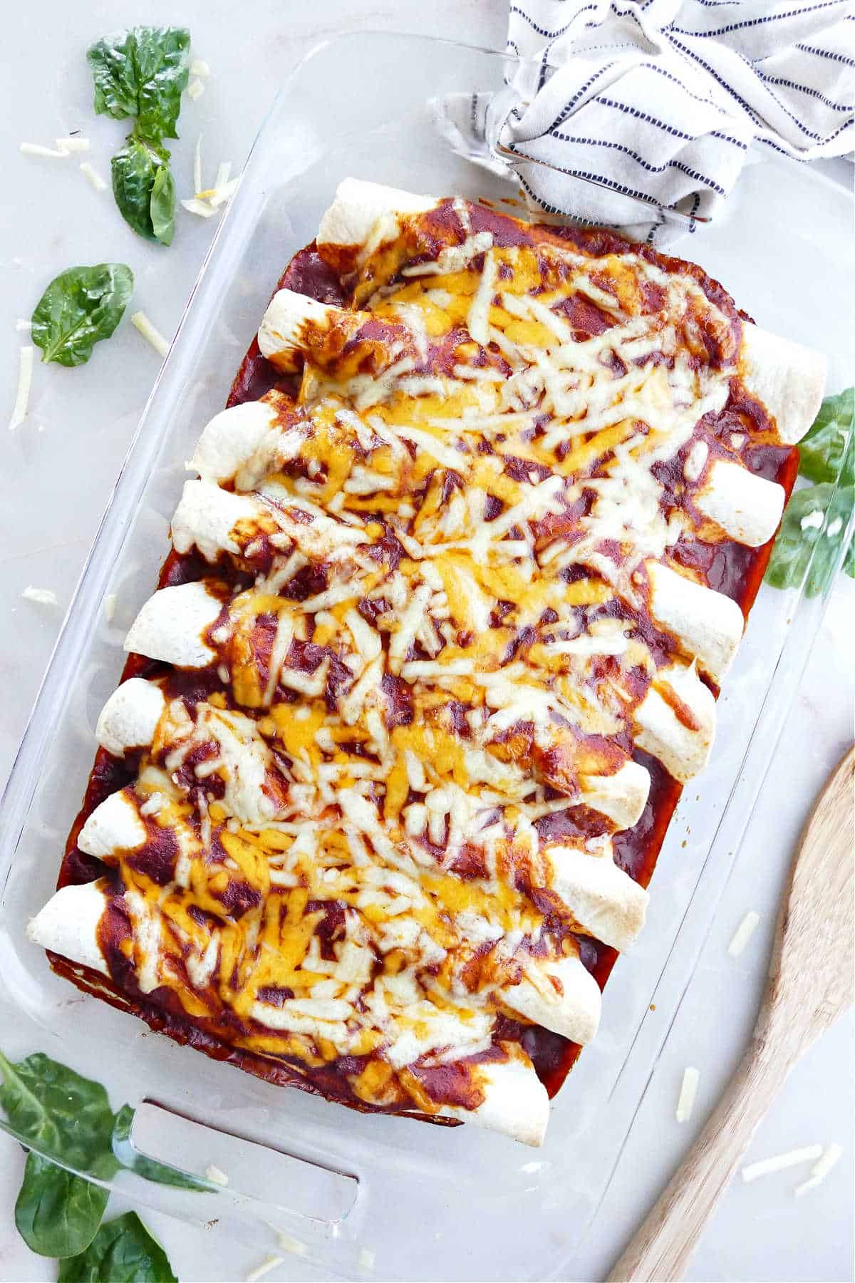 black bean and spinach enchiladas assembled in a rectangular baking dish on a counter