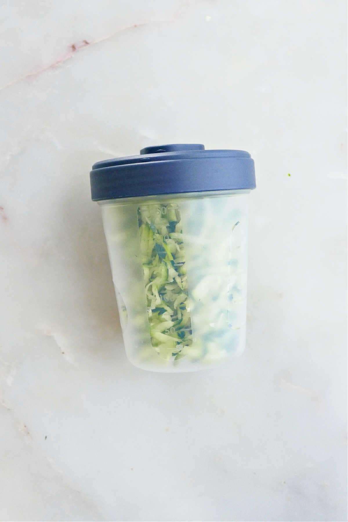 shredded zucchini in a freezer-safe container on a counter