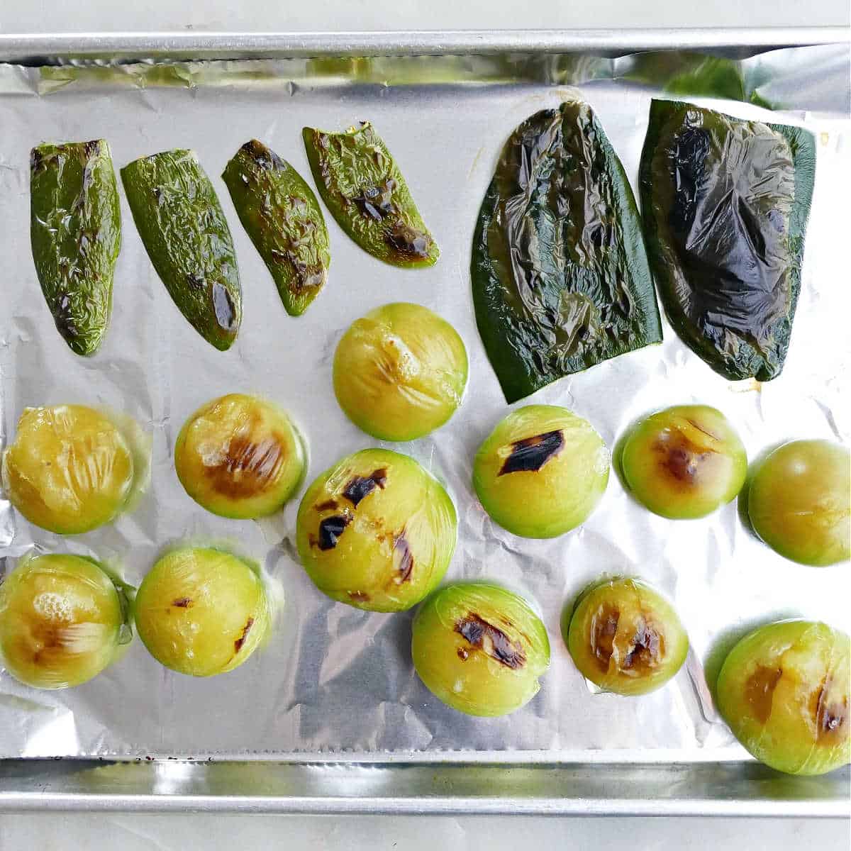 broiled tomatillos, jalapeños, and poblano peppers on a lined baking dish