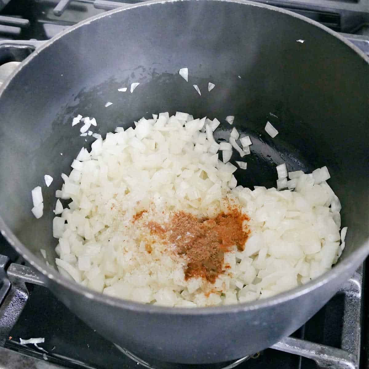 onions cooking with spices in olive oil in a soup pot on a stove