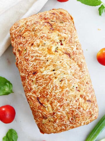 loaf of vegetable bread on a counter surrounded by ingredients and a napkin
