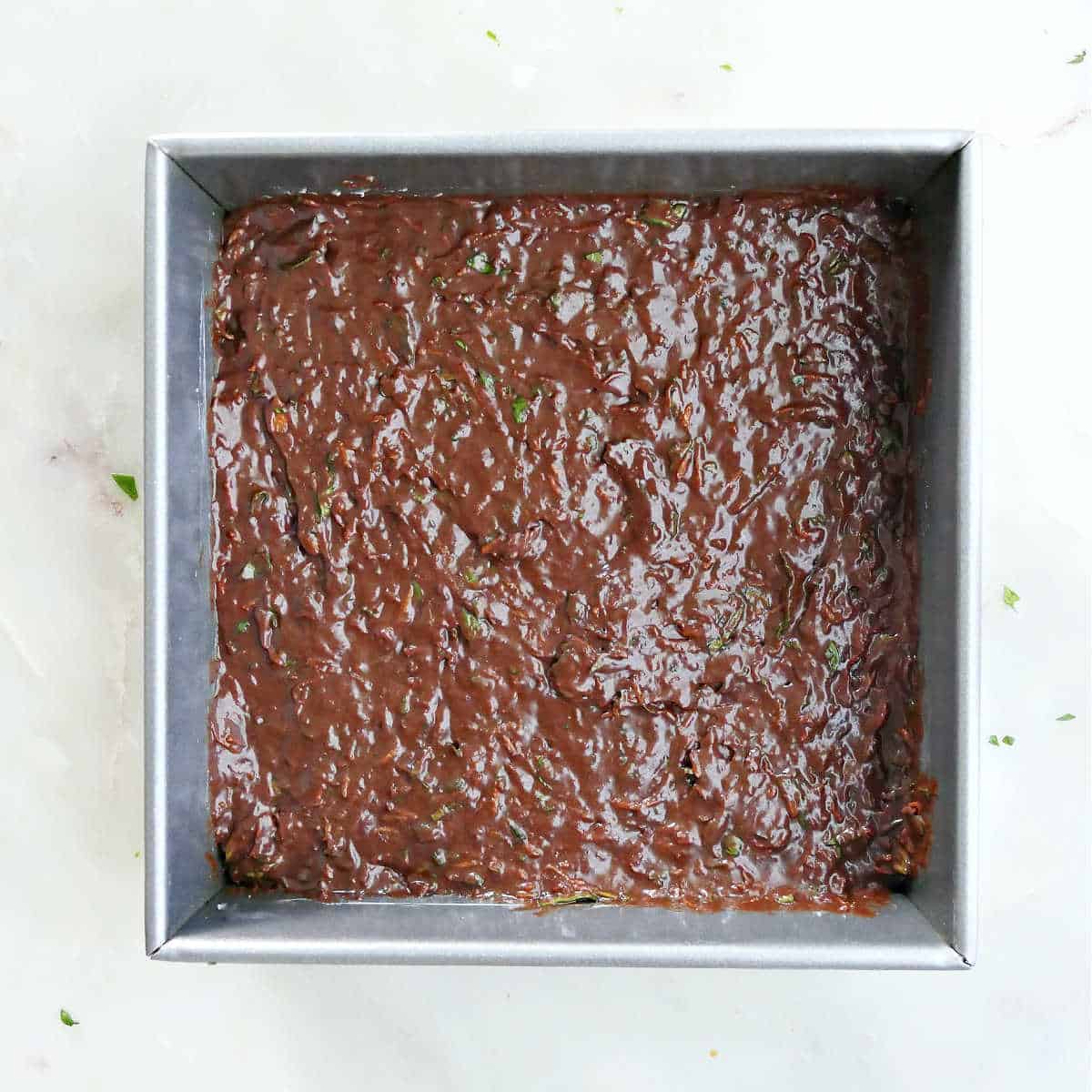 veggie brownie batter spread out in a baking dish on a counter before baking