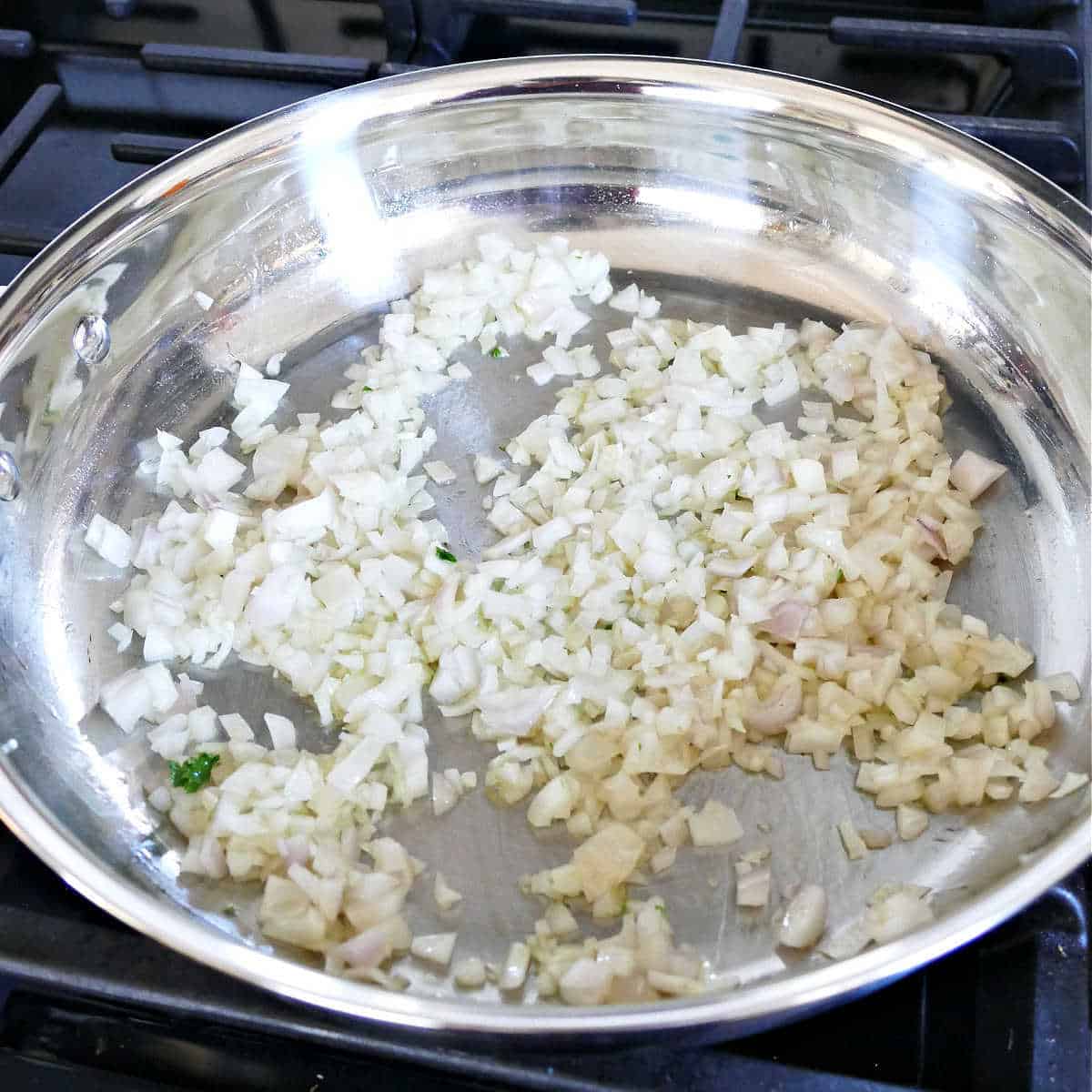 diced shallot cooking in olive oil in a large skillet on the stove