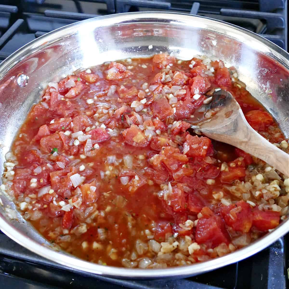 tomatoes, shallots, garlic, and spices cooking in a skillet on the stove