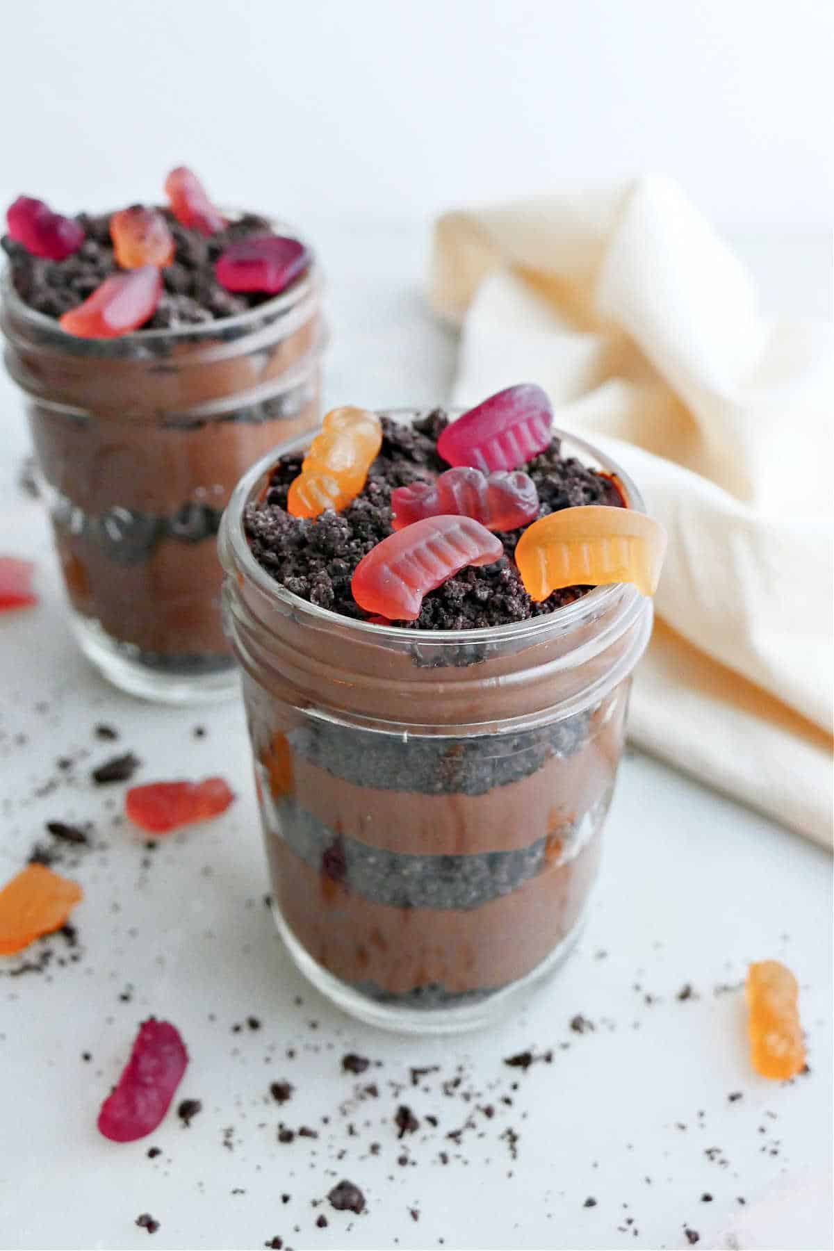two dirt cups made with layers of tofu pudding, Oreo crumbs, and gummy candies