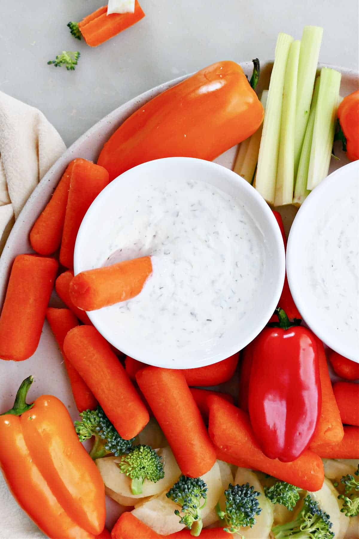 carrot stick being dipped into Greek yogurt dip on a veggie tray