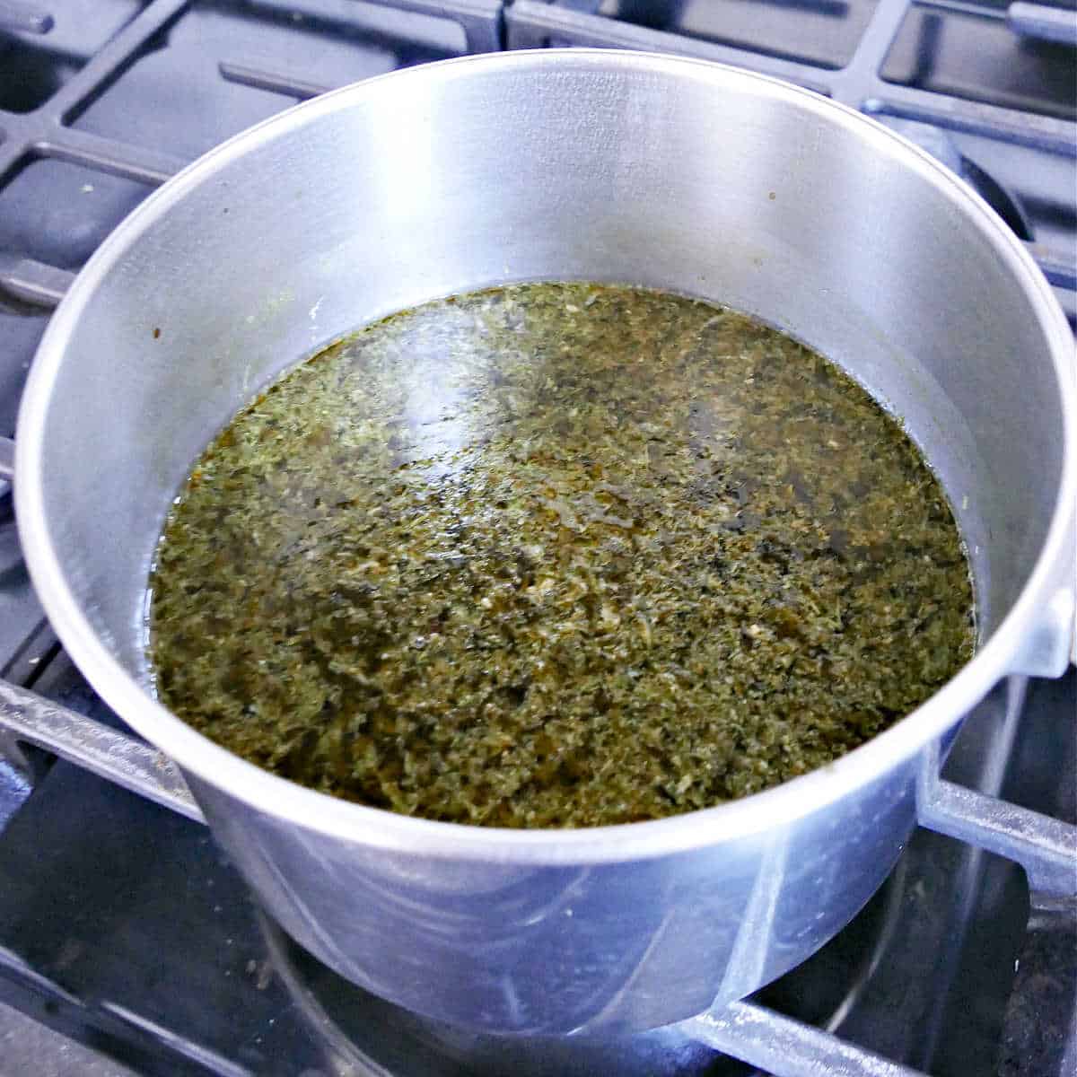 vegetable broth simmering with lemon juice and pesto on a stove