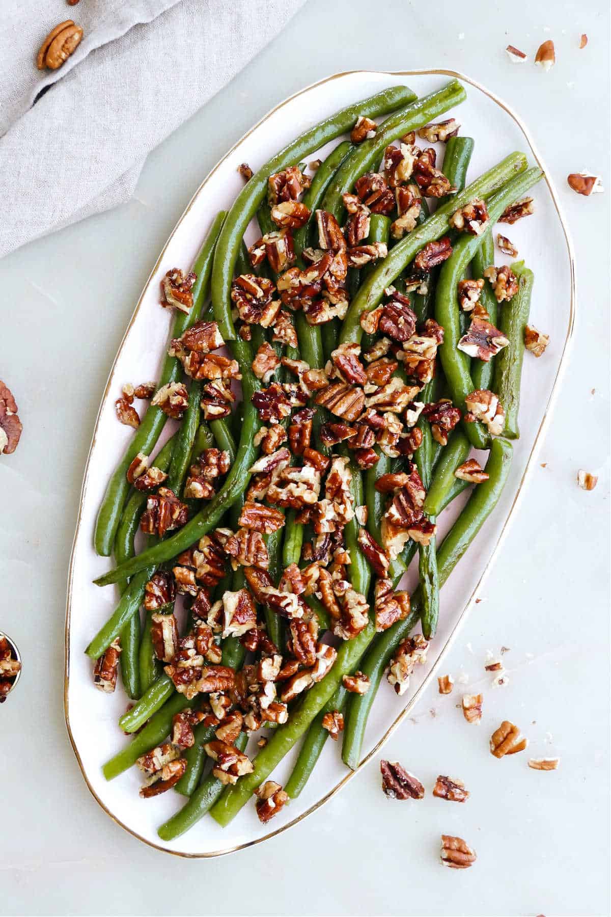 serving dish with steamed green beans and maple pecans on a counter