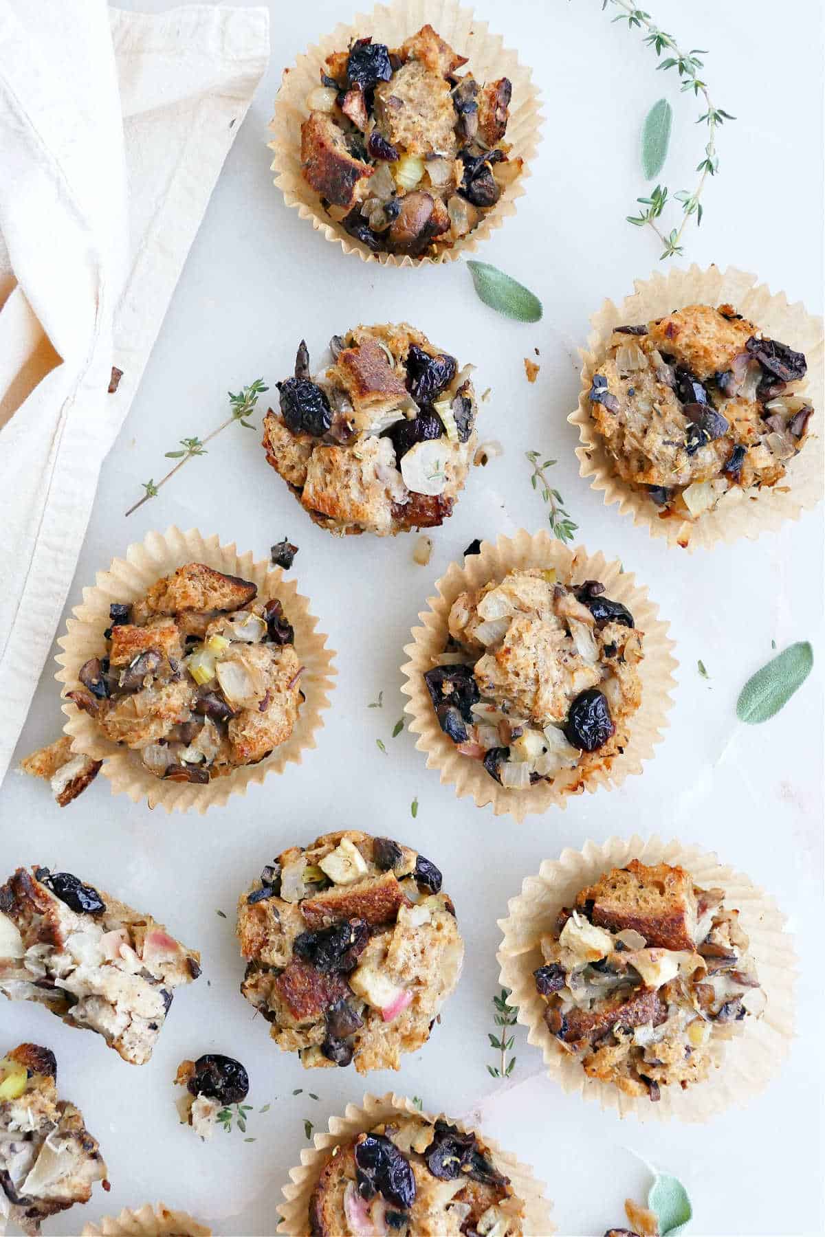 stuffing muffins on a counter next to thyme and sage leaves and a napkin