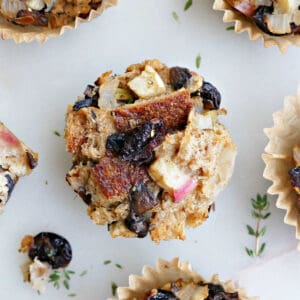 stuffing muffin with dried cranberries surrounded by more muffins on a counter