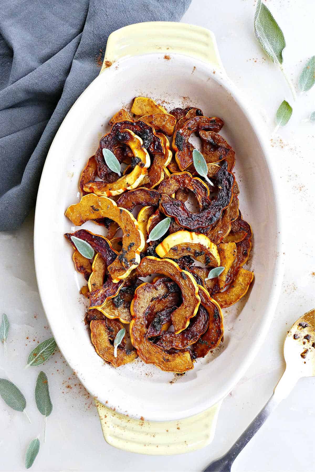 sautéed delicata squash in an oval serving tray topped with sage