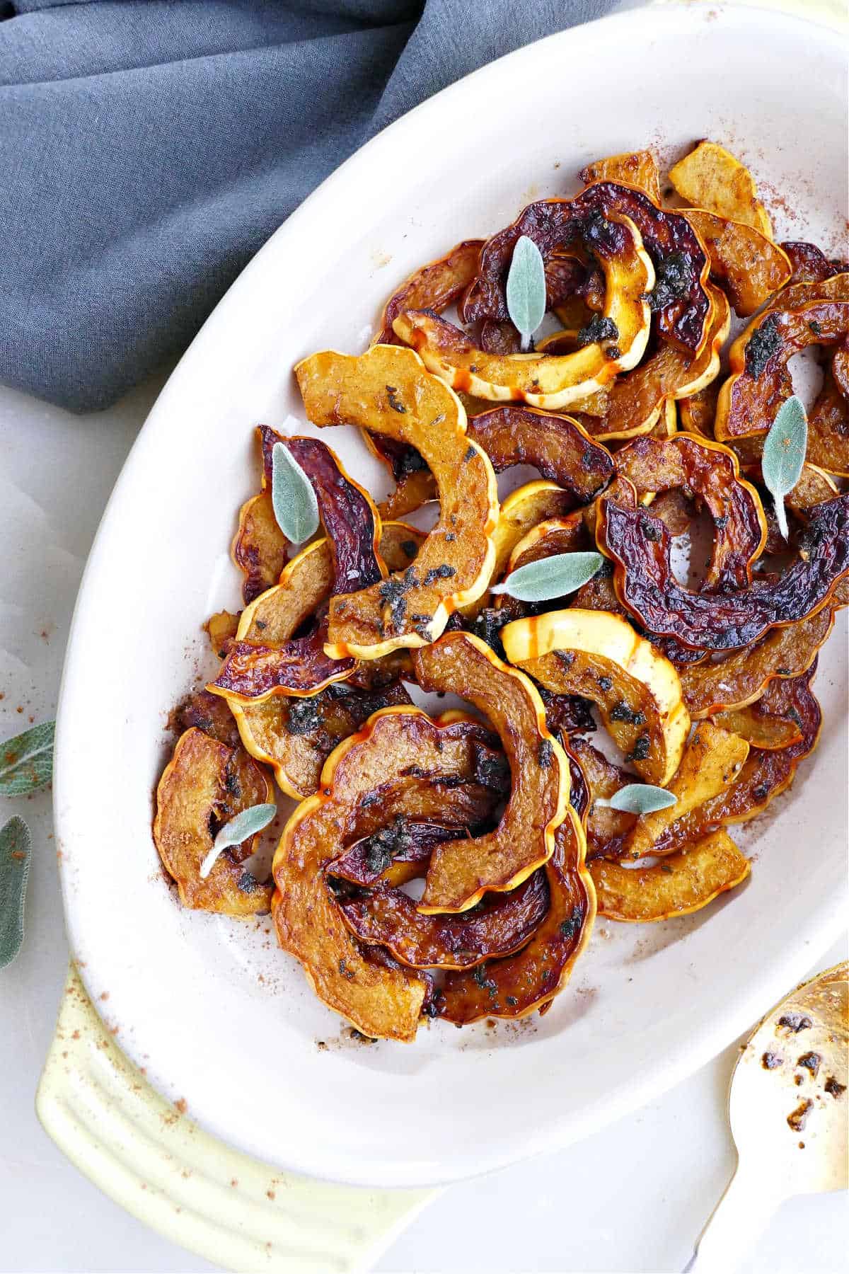 pan fried delicata squash with sage leaves in a serving tray on a counter
