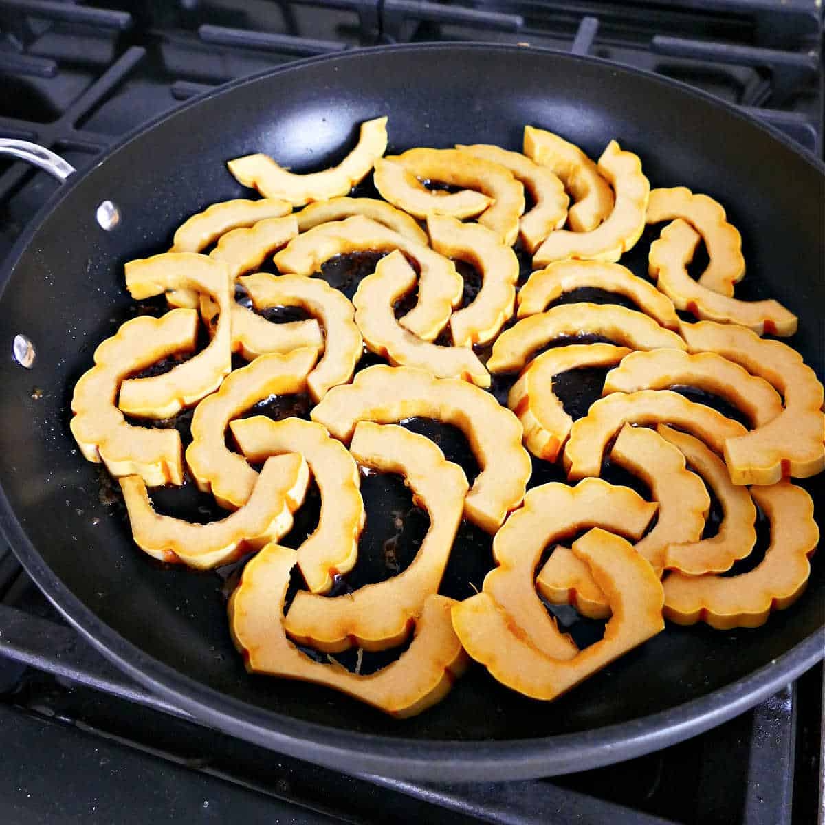 delicata squash pieces added to a skillet with oil, cinnamon, and sage