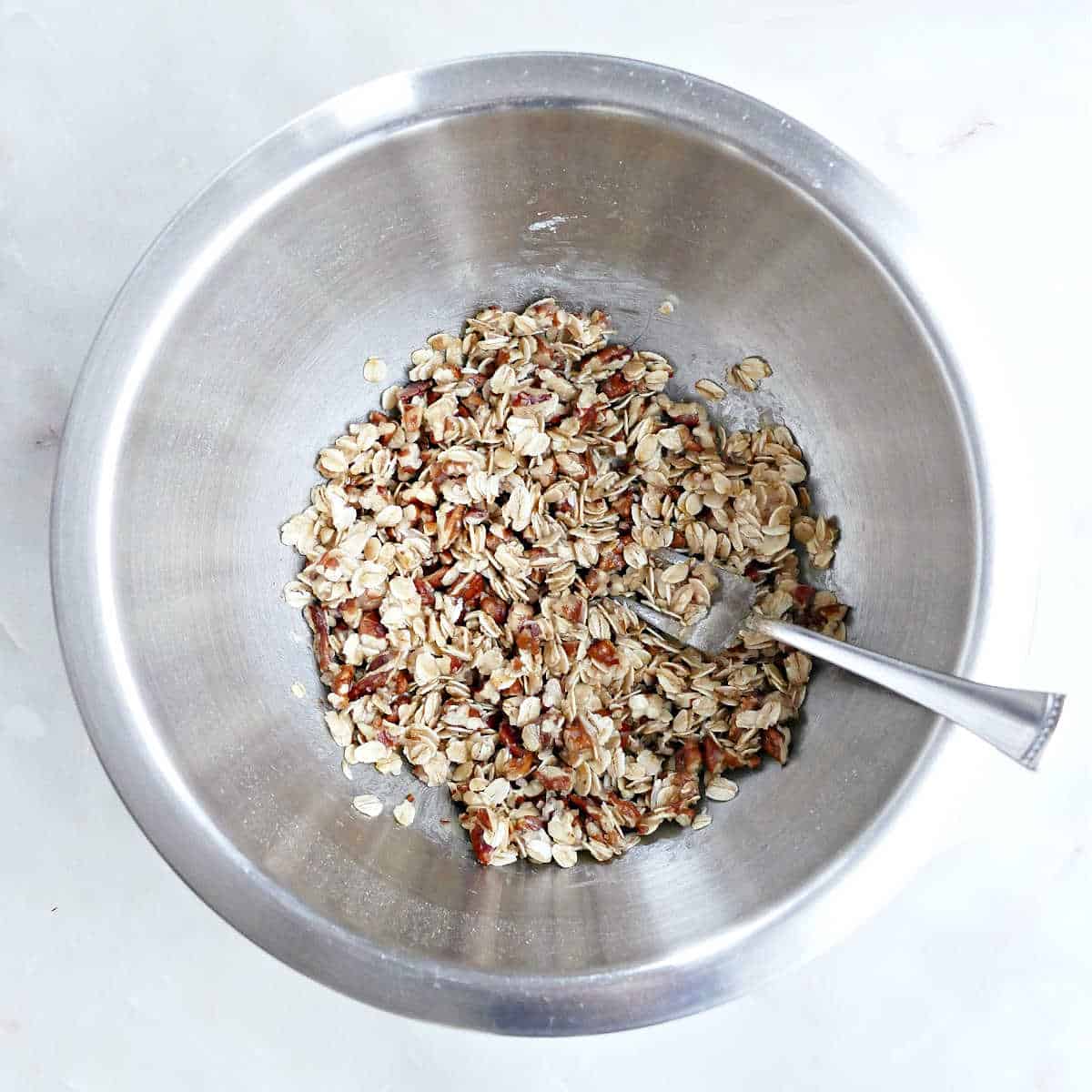 chopped pecans, oats, flour, and coconut oil mixed together in a bowl