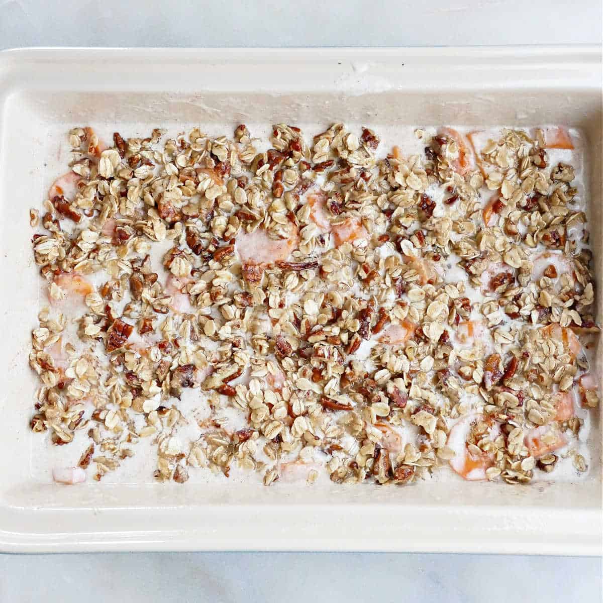 carrots in coconut milk sauce topped with pecan streusel in a dish before baking