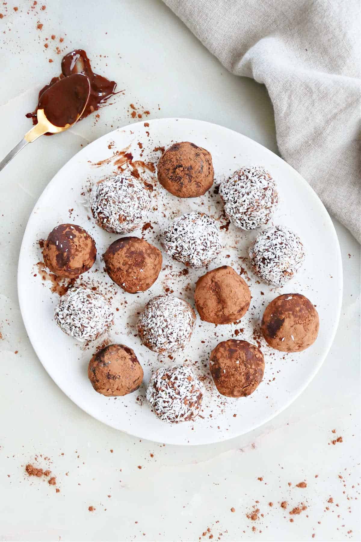 14 avocado truffles dusted with cocoa powder or coconut on a plate