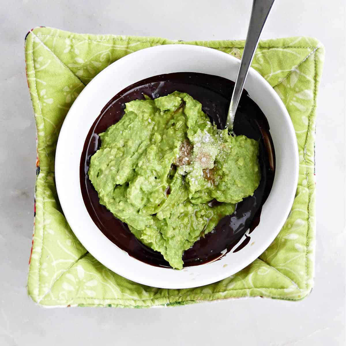 melted dark chocolate, mashed avocado, vanilla, and salt in a bowl with a spoon