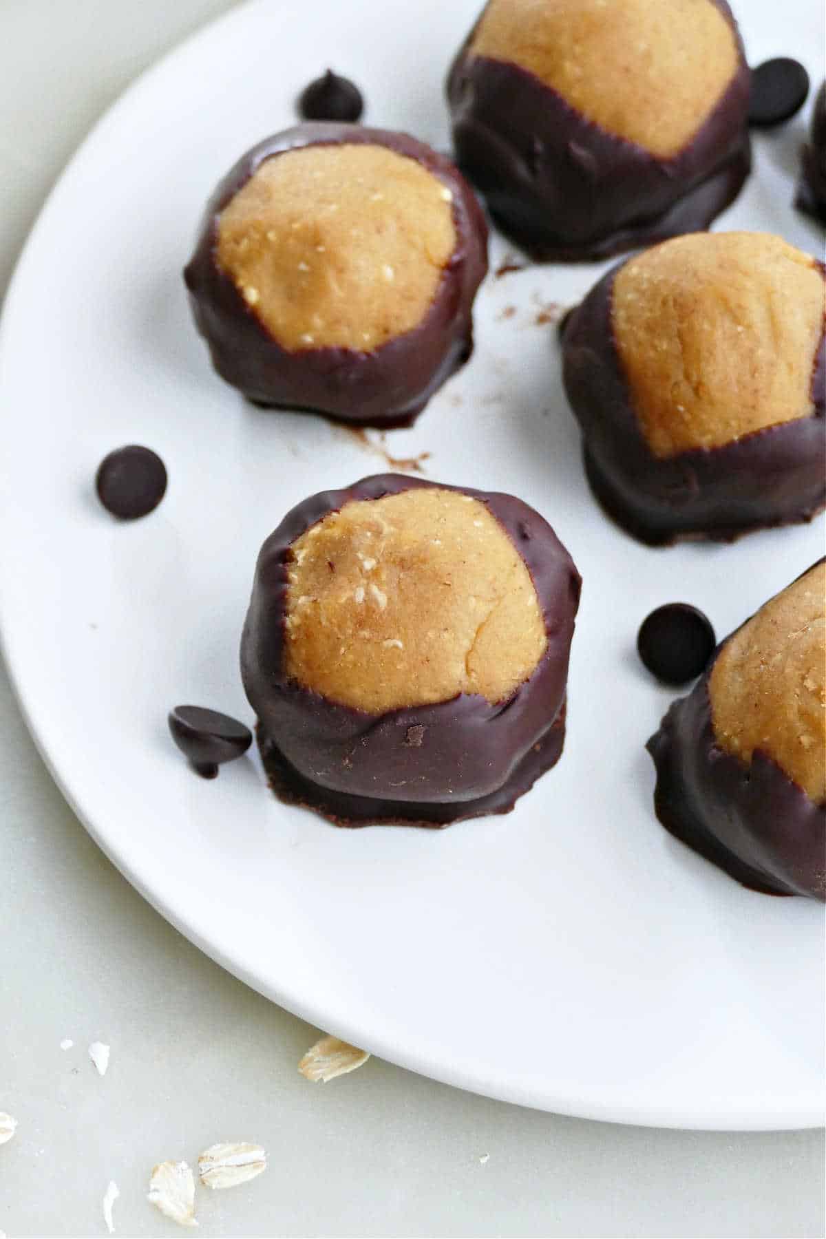 vegan buckeyes coated in chocolate on a plate with chocolate chips