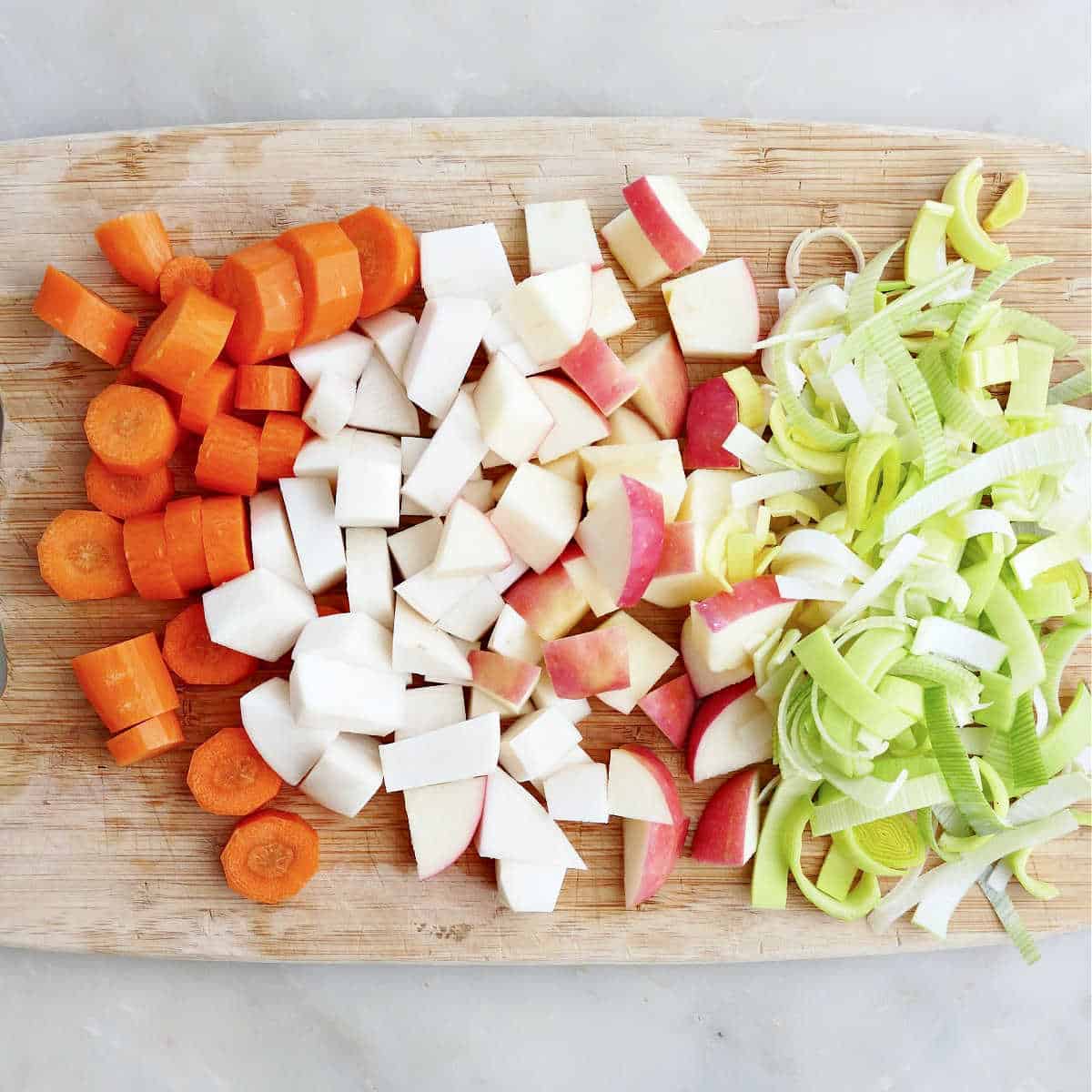 sliced carrots, turnips, apples, and leek on a cutting board