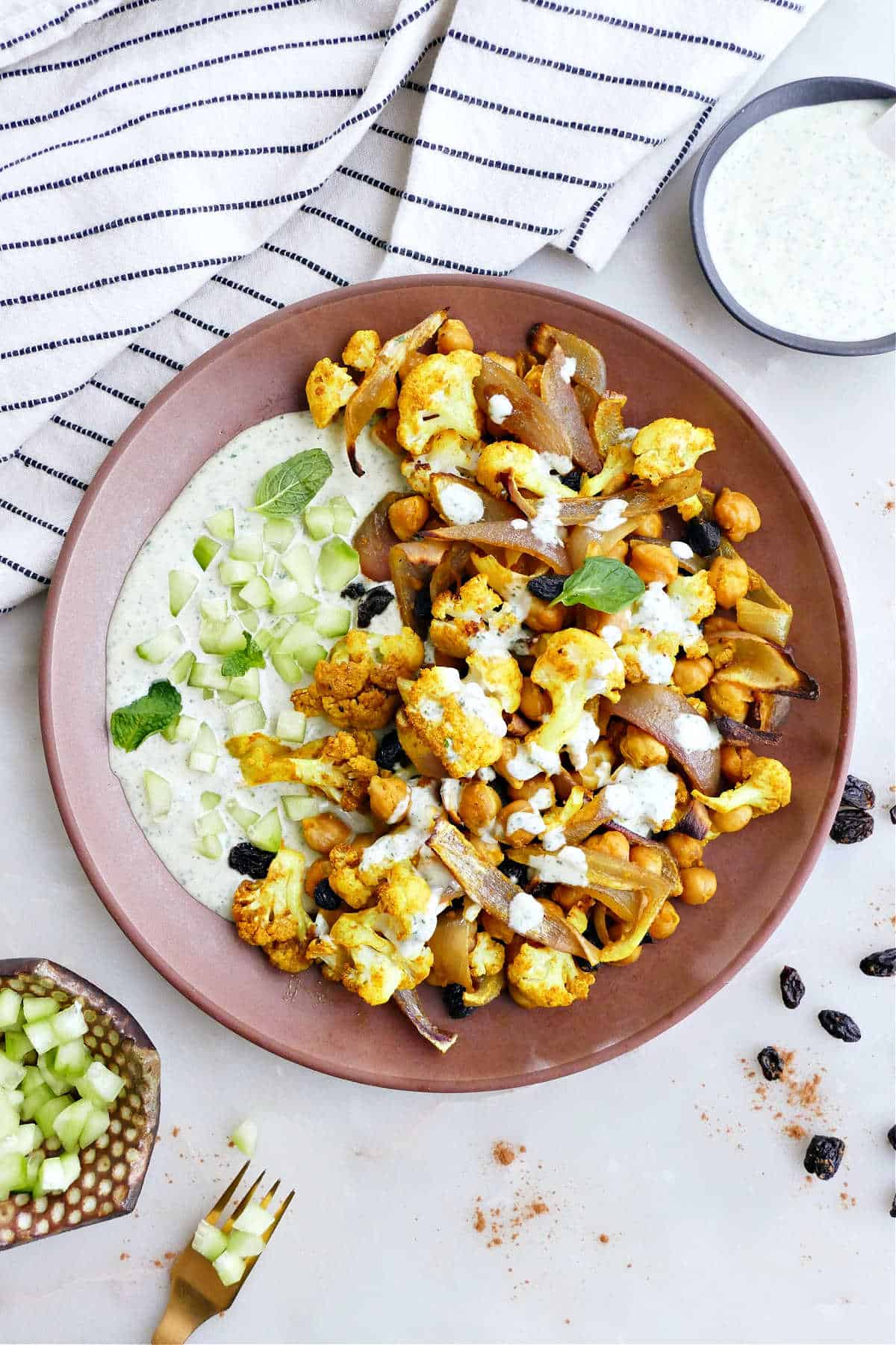 roasted cauliflower and chickpeas with tahini sauce on a plate on a counter