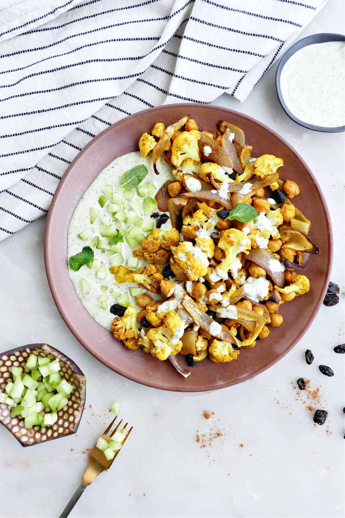 cauliflower, chickpeas, onions, and raisins paired with tahini sauce on a plate
