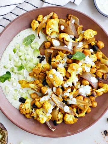 roasted cauliflower and chickpeas with tahini sauce on a plate on a counter