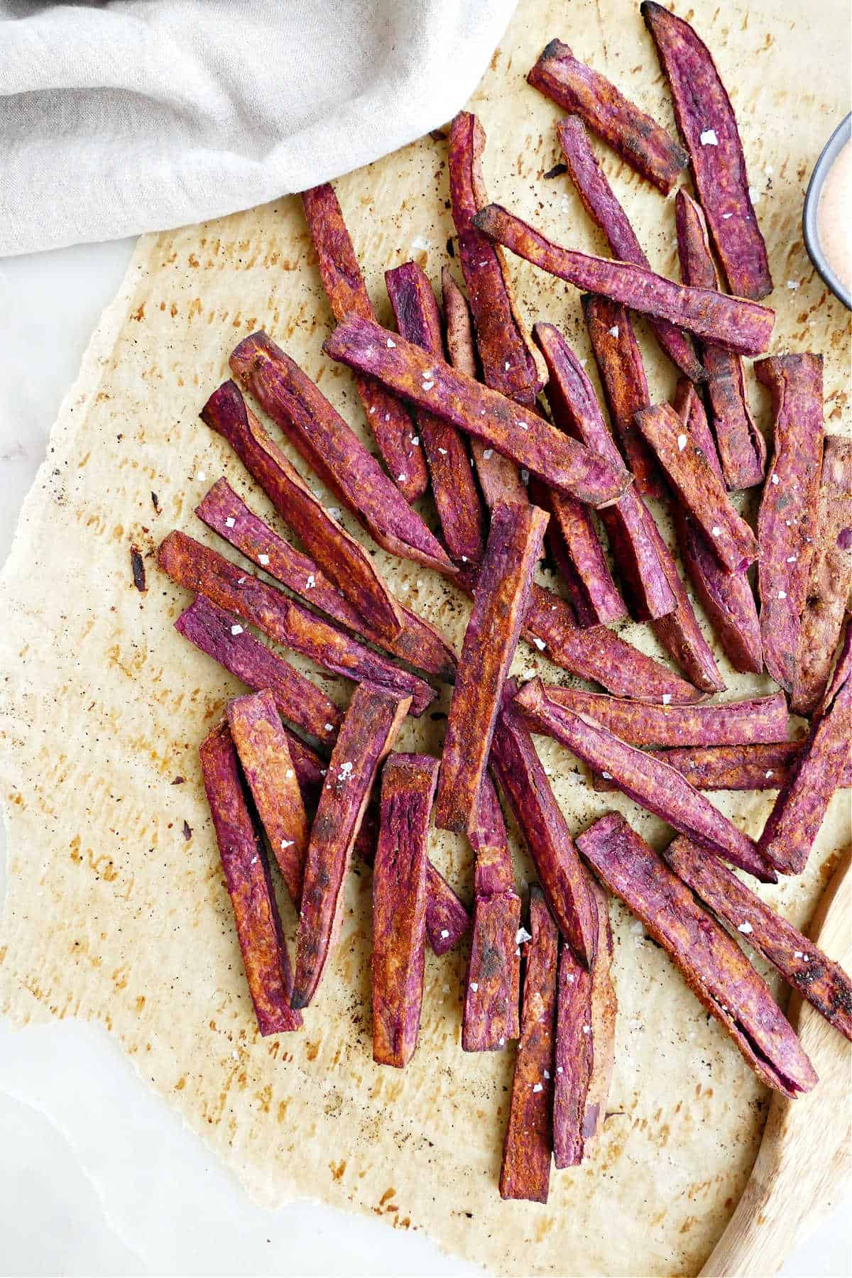 purple sweet potato fries topped with salt on a piece of parchment paper