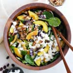 acorn squash salad in a wooden salad bowl on a counter next to toppings