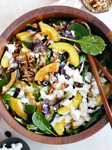acorn squash salad in a wooden salad bowl on a counter next to toppings