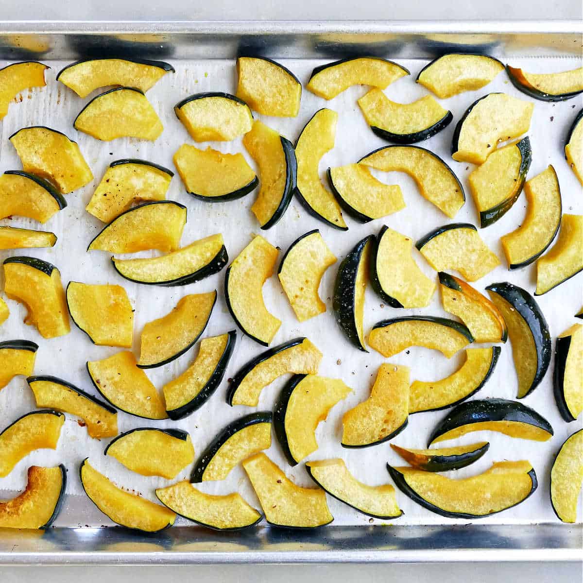roasted acorn squash wedges on a lined baking sheet on a counter