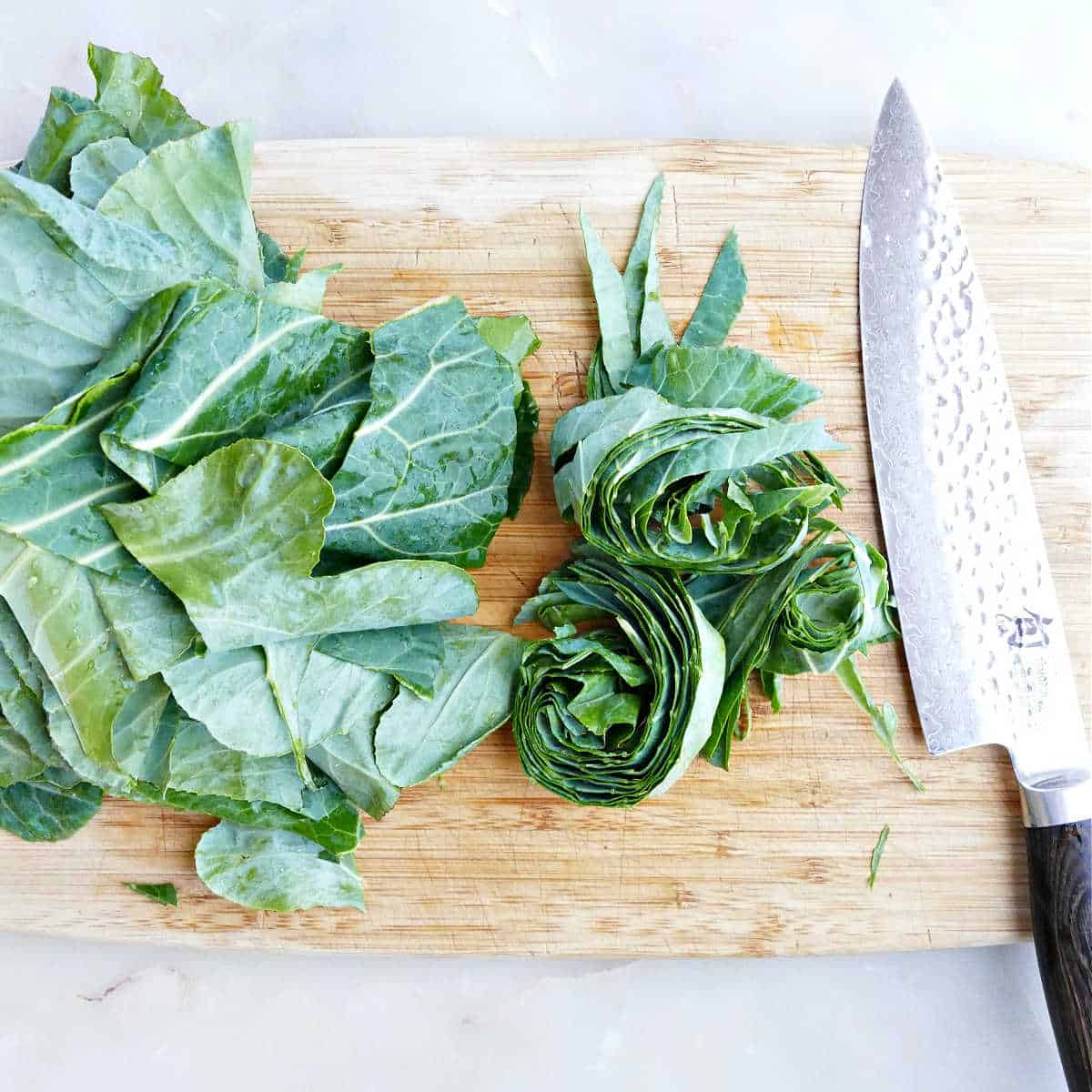 collard greens sliced into strips on a cutting board next to a knife