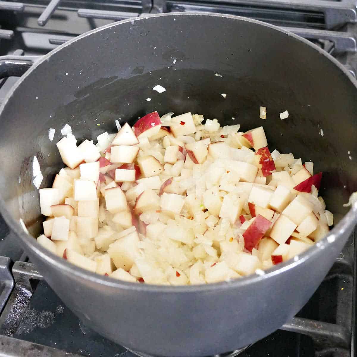 onion, garlic, potatoes, and spices cooking in olive oil in a soup pot
