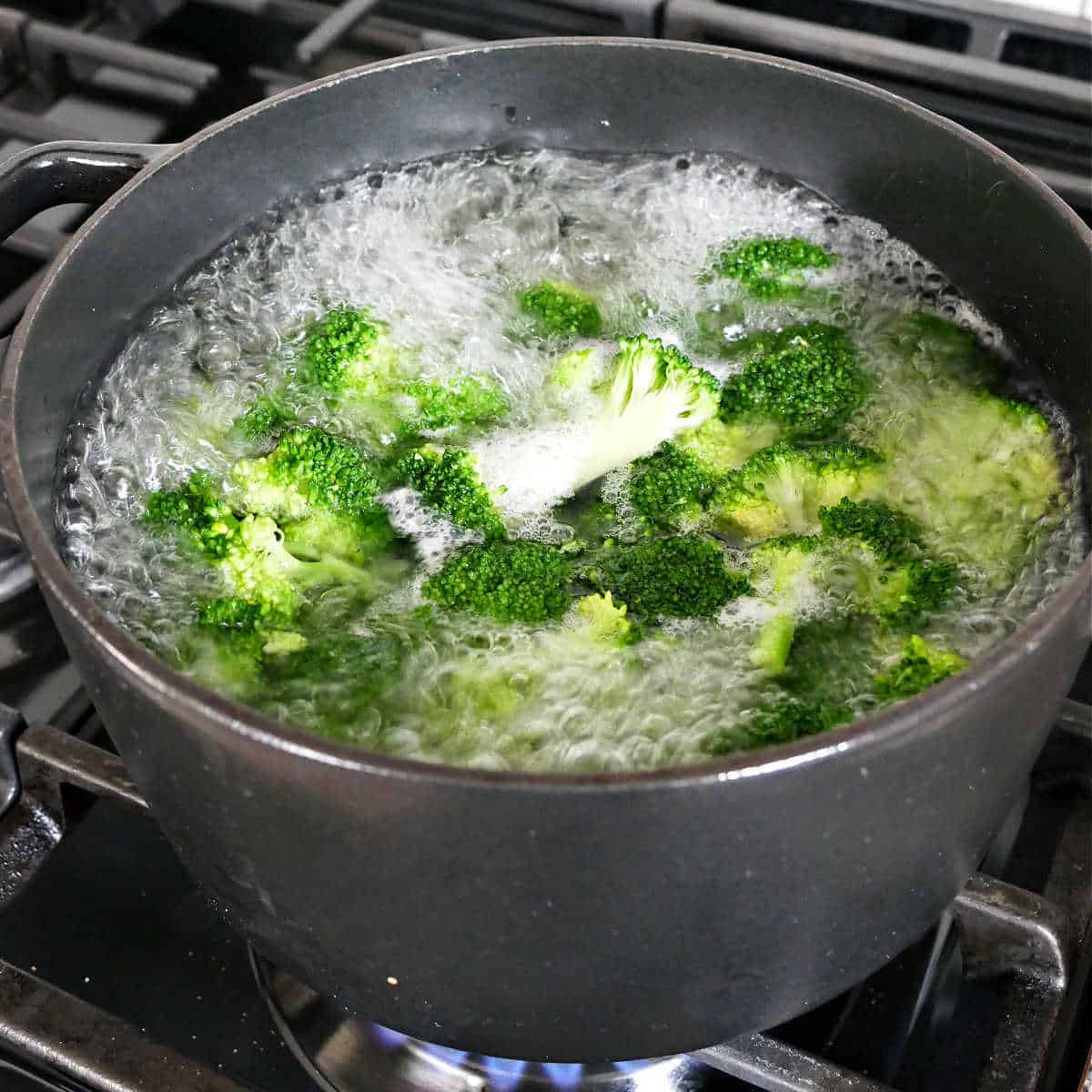 broccoli being blanched in a pot of boiling water on a stovetop