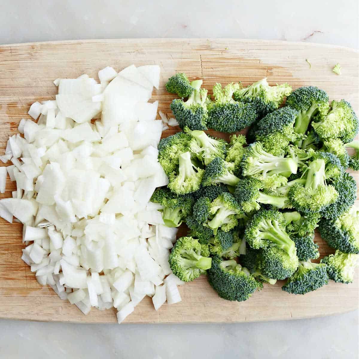 diced onion and chopped broccoli on a bamboo cutting board