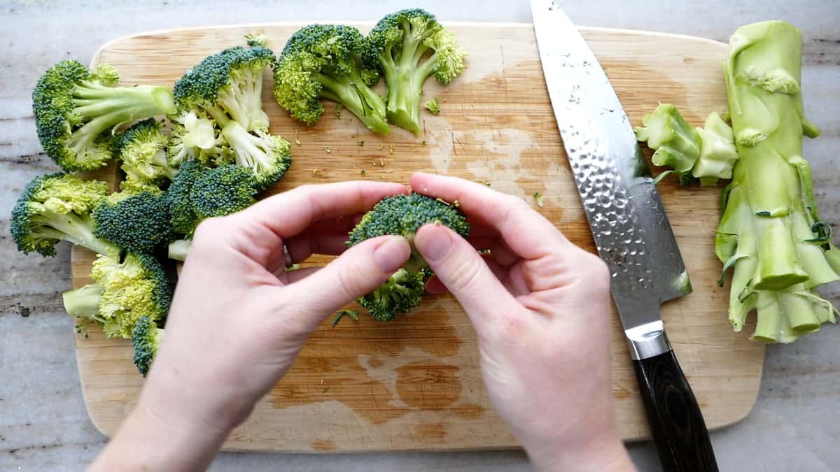 woman using hands to tear broccoli floret into small pieces