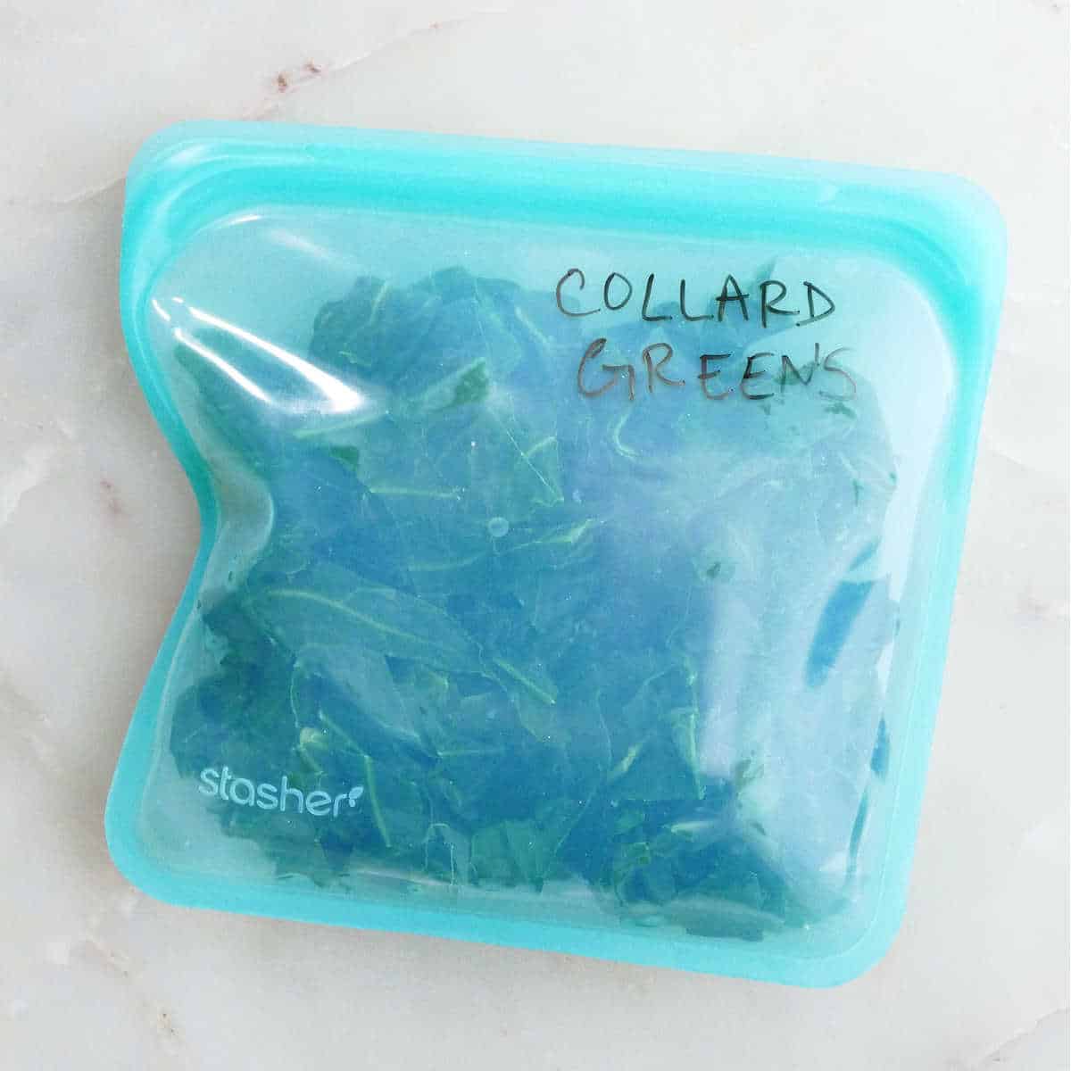 frozen balls of collard greens in a labeled silicone freezer bag on a counter