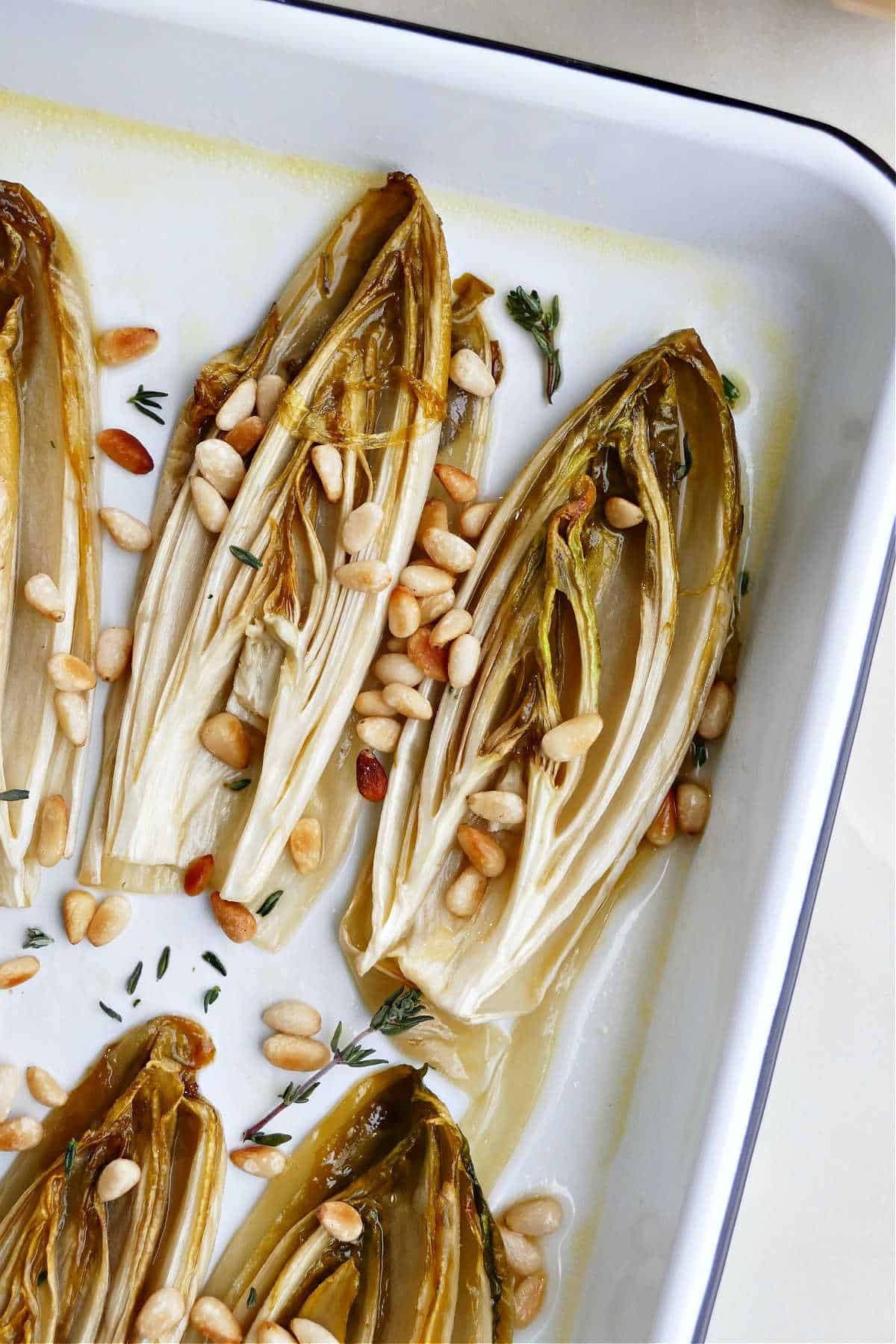 roasted endive halves topped with pine nuts and thyme on a try