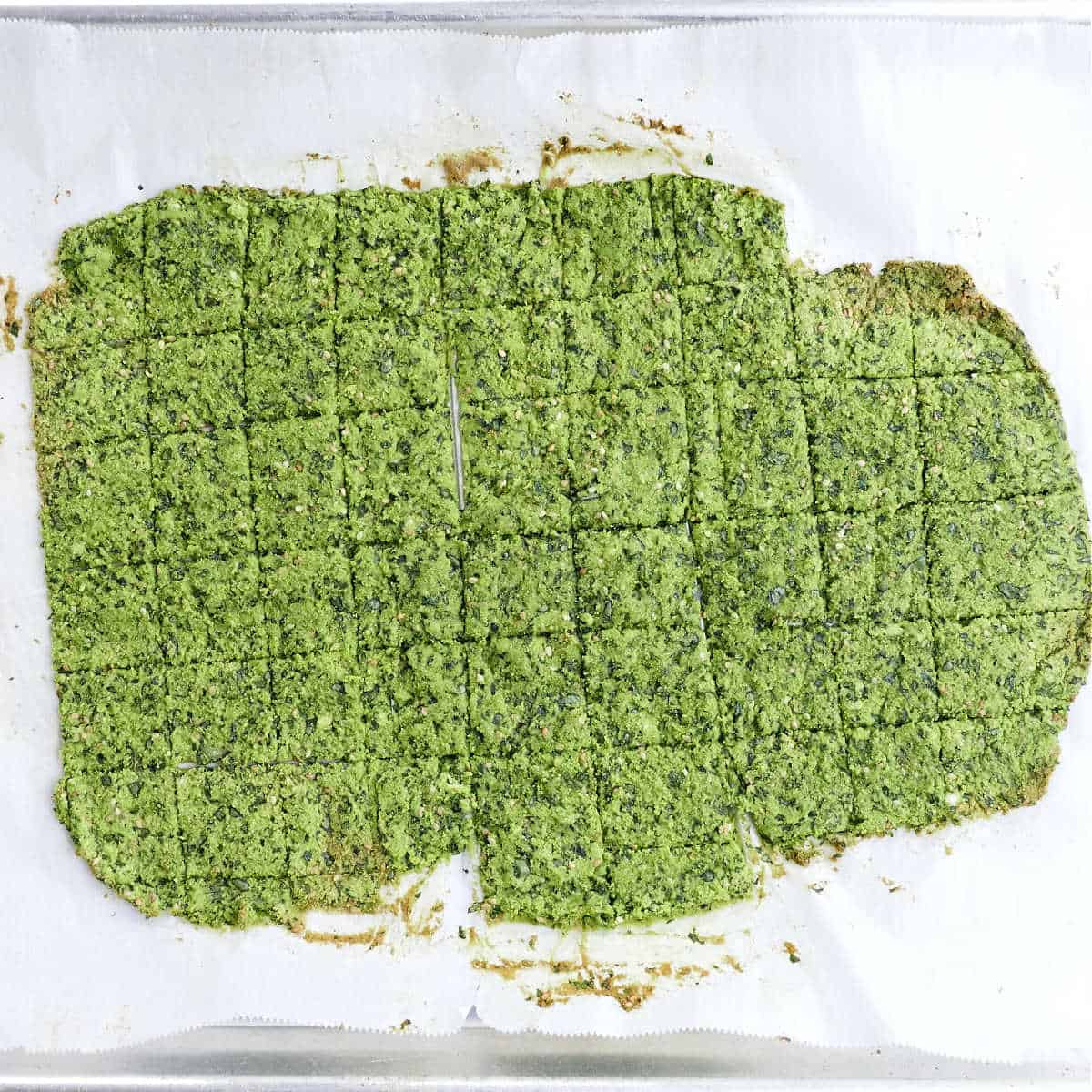 Spinach crackers after being baked on parchment paper.
