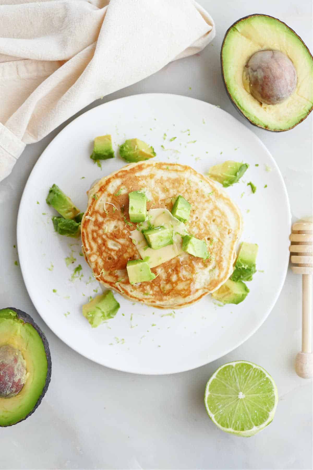 A stack of avocado pancakes on a plate topped with diced avocado.
