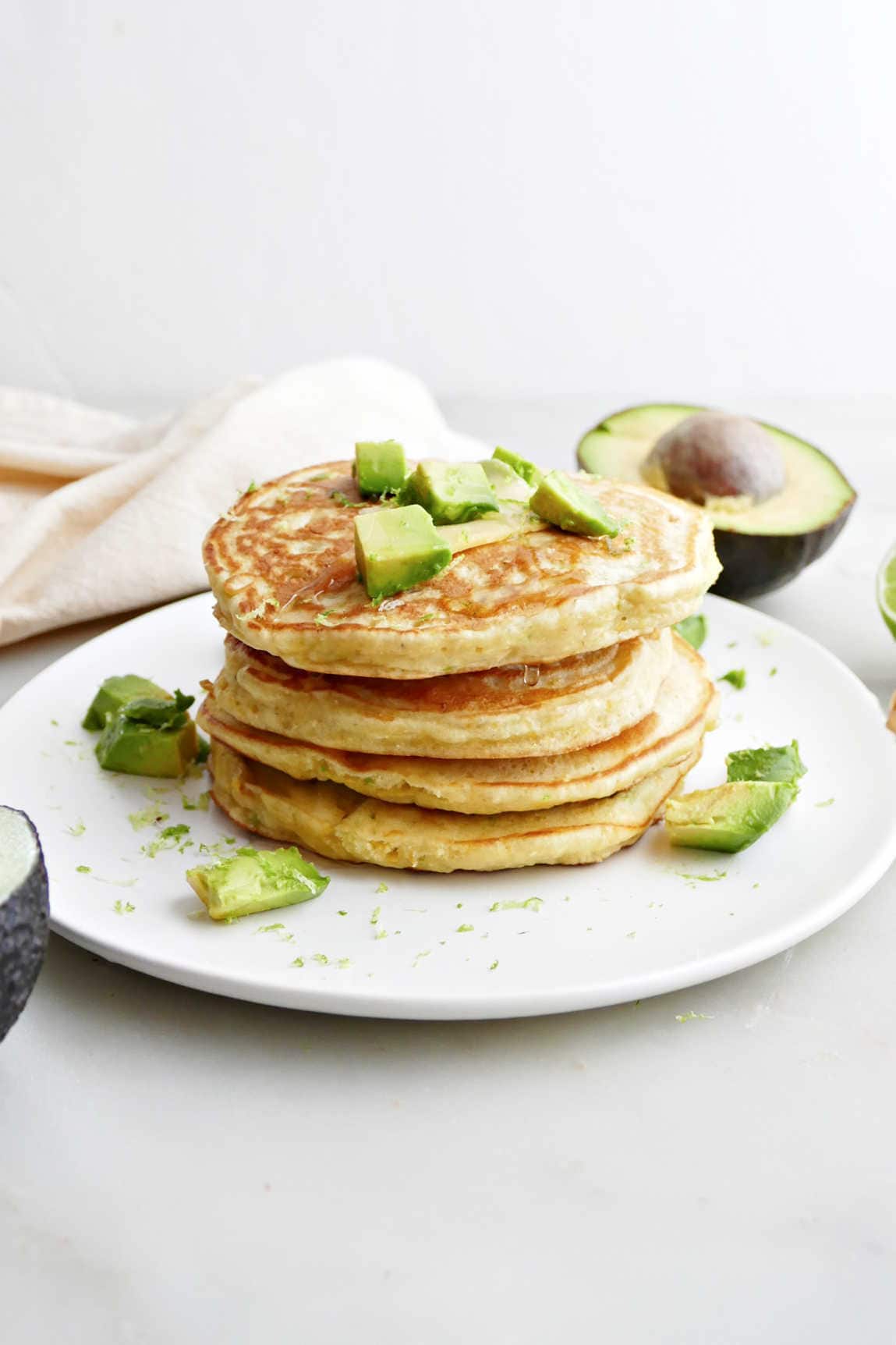 A stack of four avocado pancakes on a white plate.