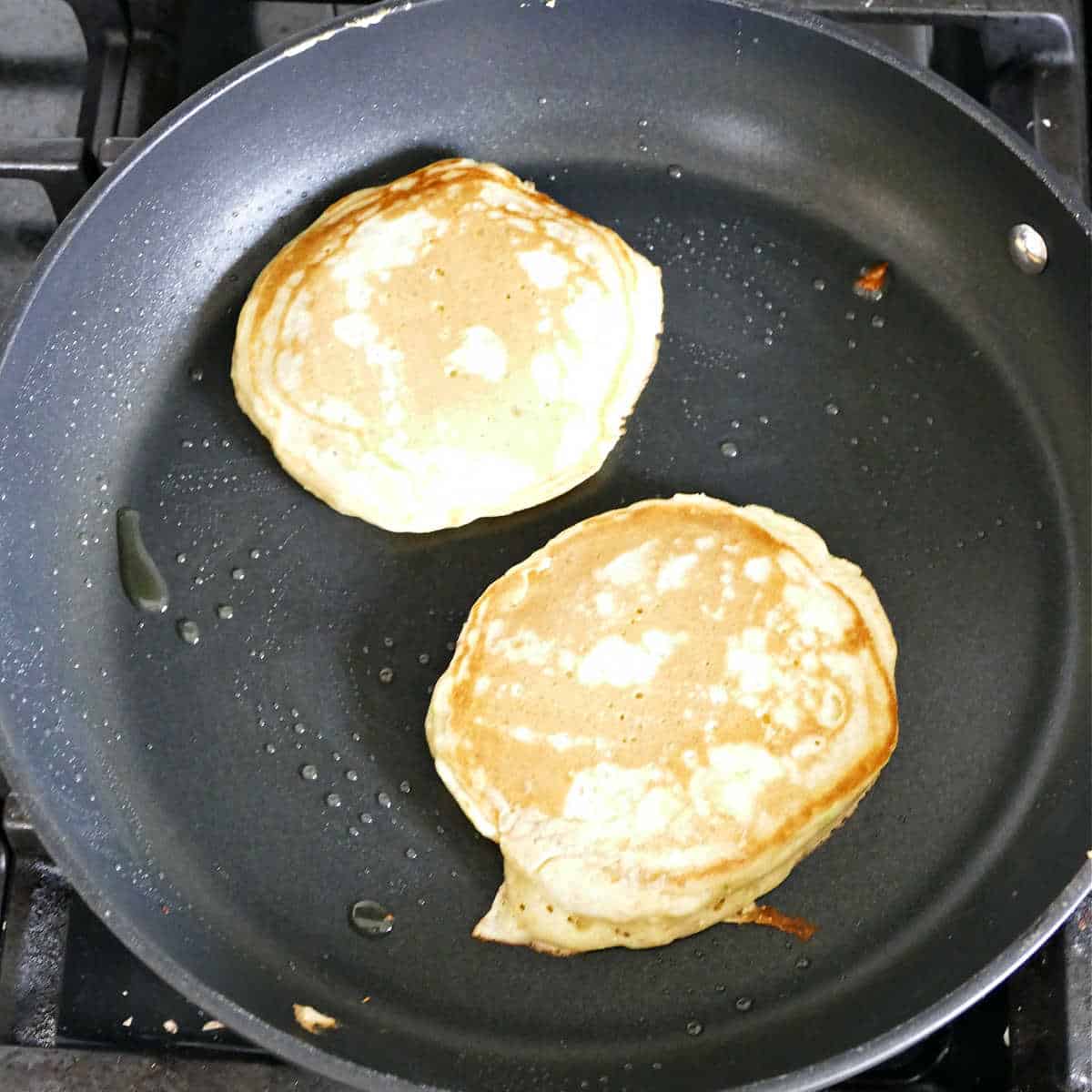 Avocado pancakes in a large pan after flipping.