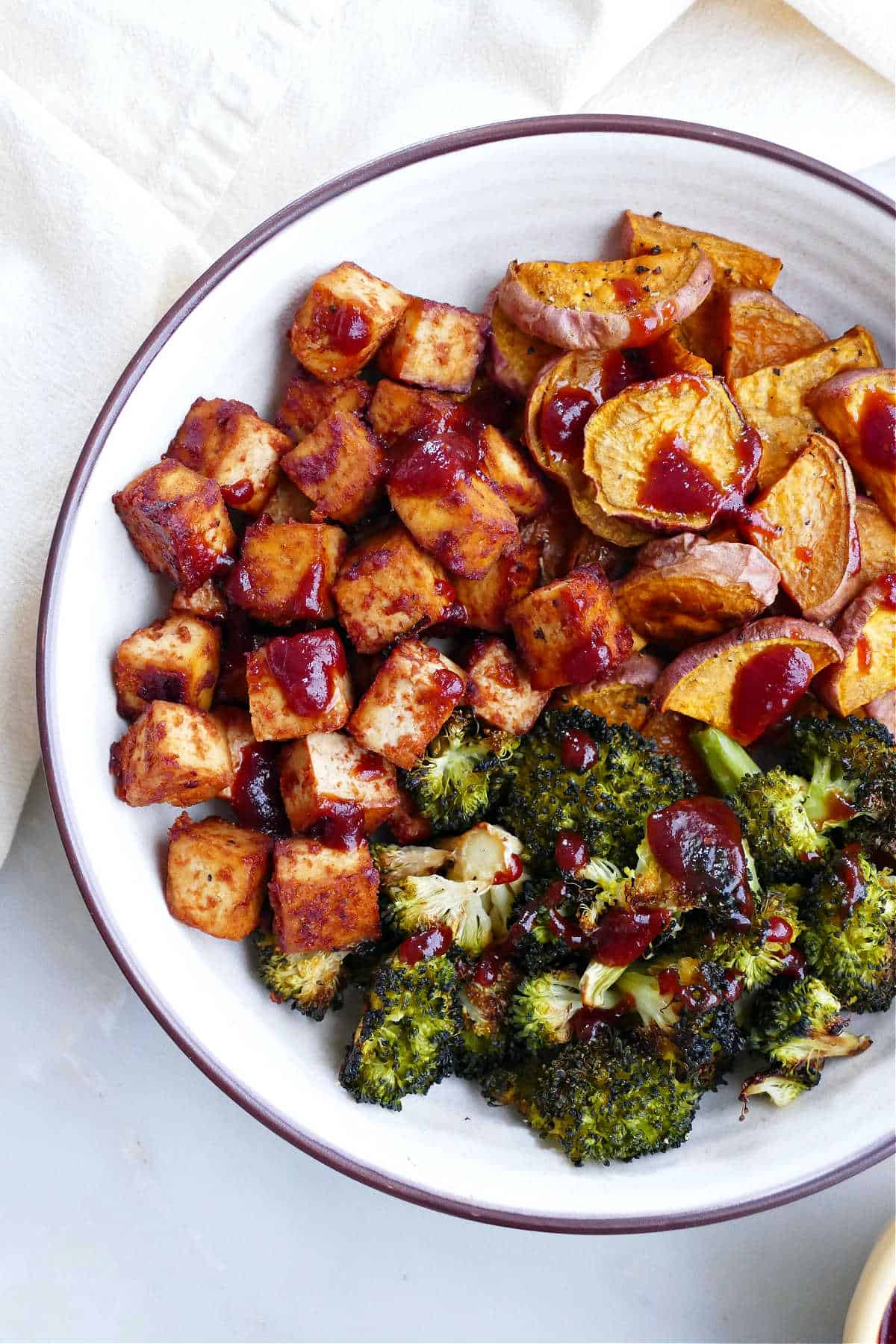 Bbq marinated tofu and broccoli with barbecue sauce drizzled over top.
