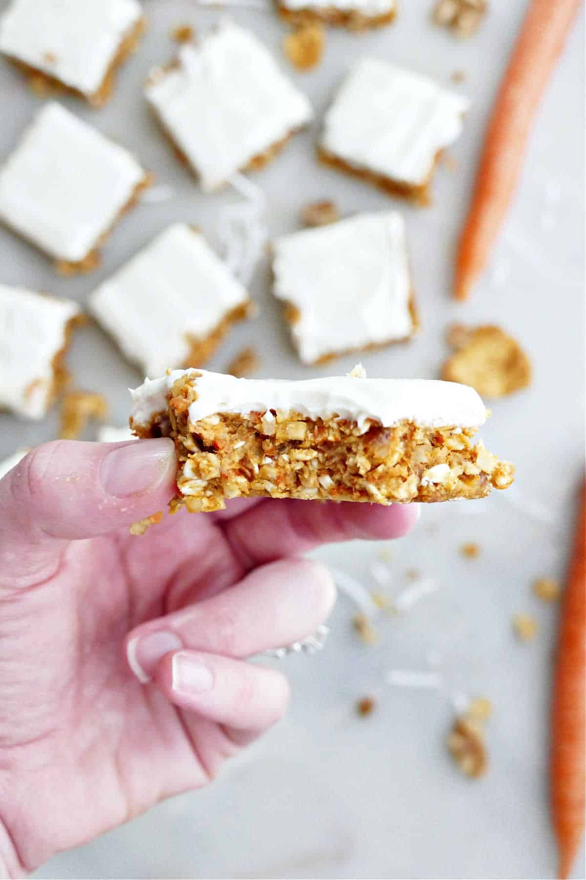 Holding a no bake carrot cake bar with a bite taken out.