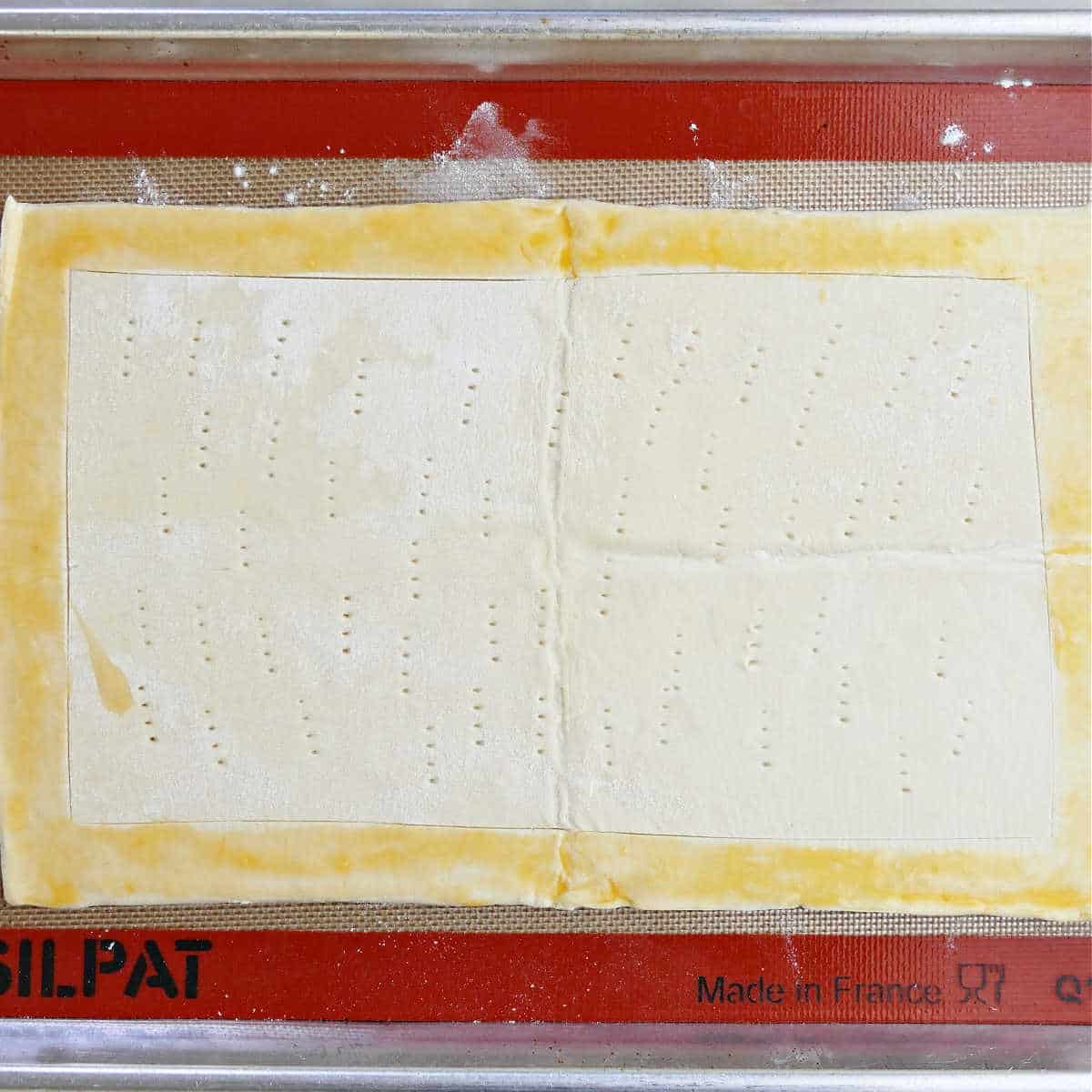 Puff pastry that has been forked on a baking pan.